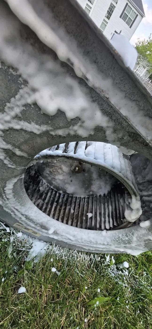 Technician performing coil cleaning during a maintenance visit